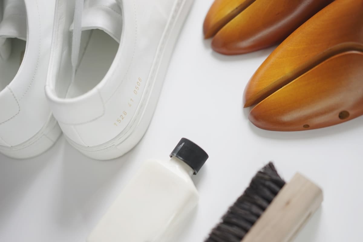 Chaussures blanches, brosse et produit d'entretien sur un plan de travail